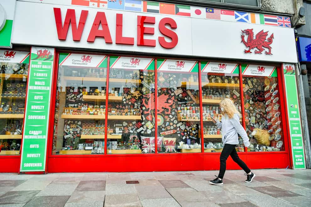 A woman wears a face covering as she walks past a shop in Cardiff