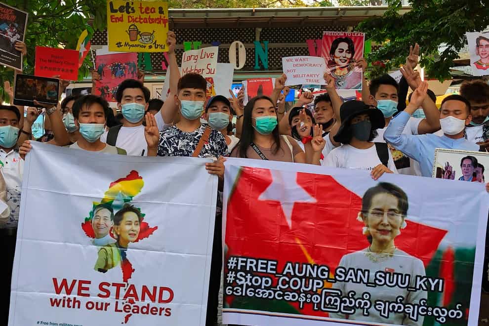 Migrant workers from Myanmar flash the three-finger protest gesture while they hold banners with images of deposed Myanmar leader Aung San Suu Kyi before participating in a march by Thai pro-democracy activists in Bangkok on Sunday
