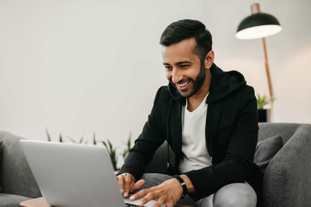 Young man smiling looking at a laptop