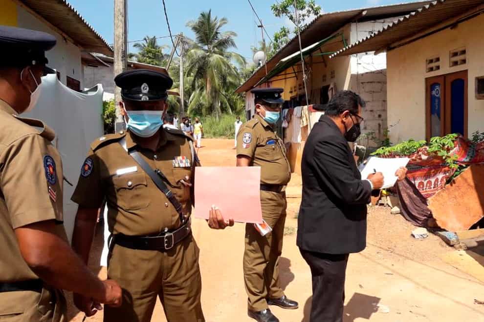Police officers outside a house where a nine-year-old girl was canned to death in Delgoda, Sri Lanka