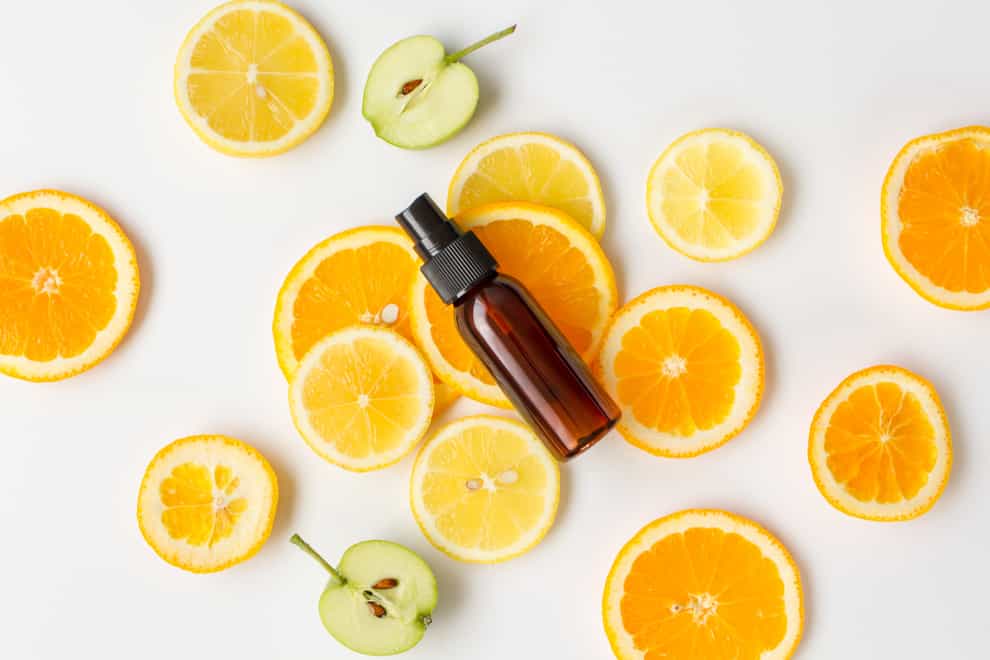 bottle of essential oil surrounded by orange slices
