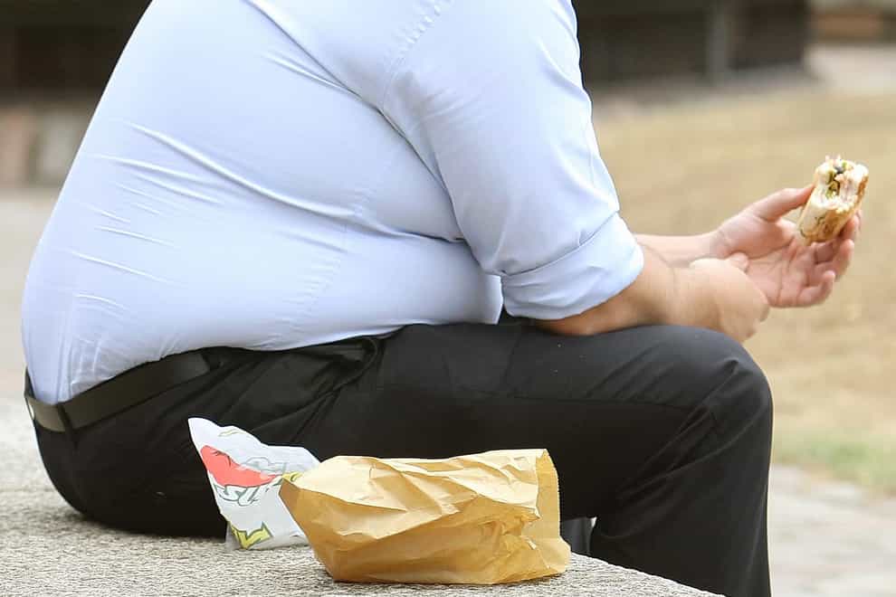An overweight man eating fast food