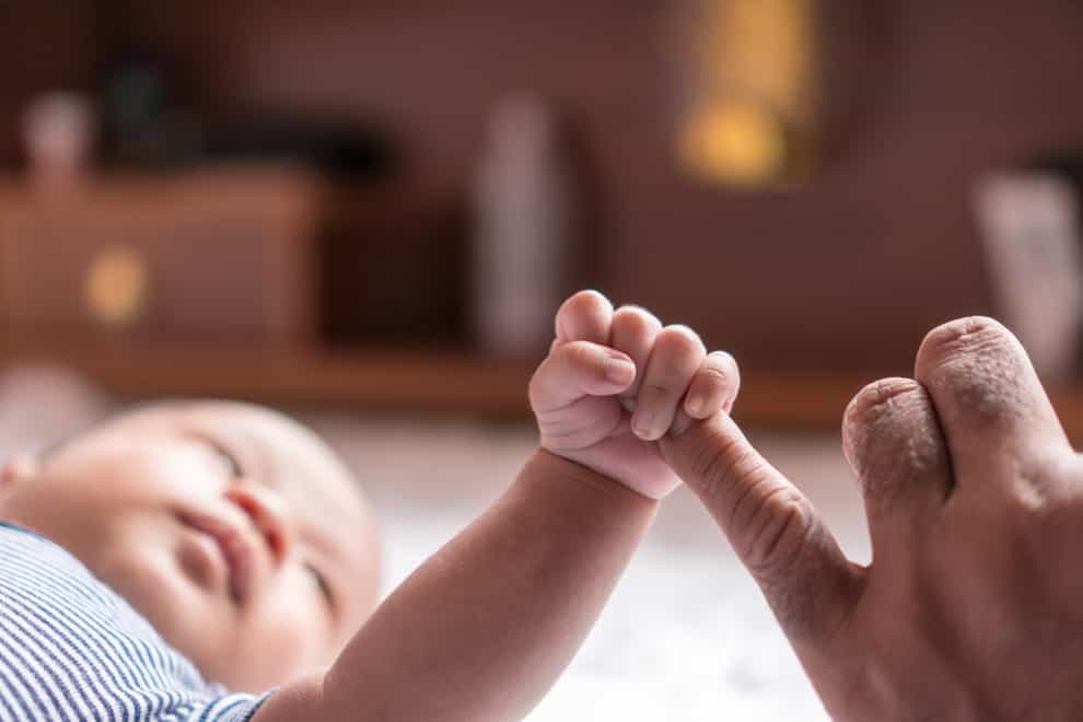 New born baby holding an adult finger
