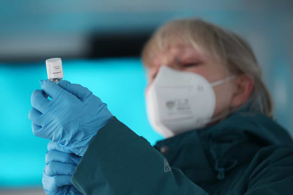 An NHS nurse prepares a dose of the Oxford-AstraZeneca Covid-19 vaccine in a modified bus, in the car park of the University of Greenwich, London (Yui Mok/PA)
