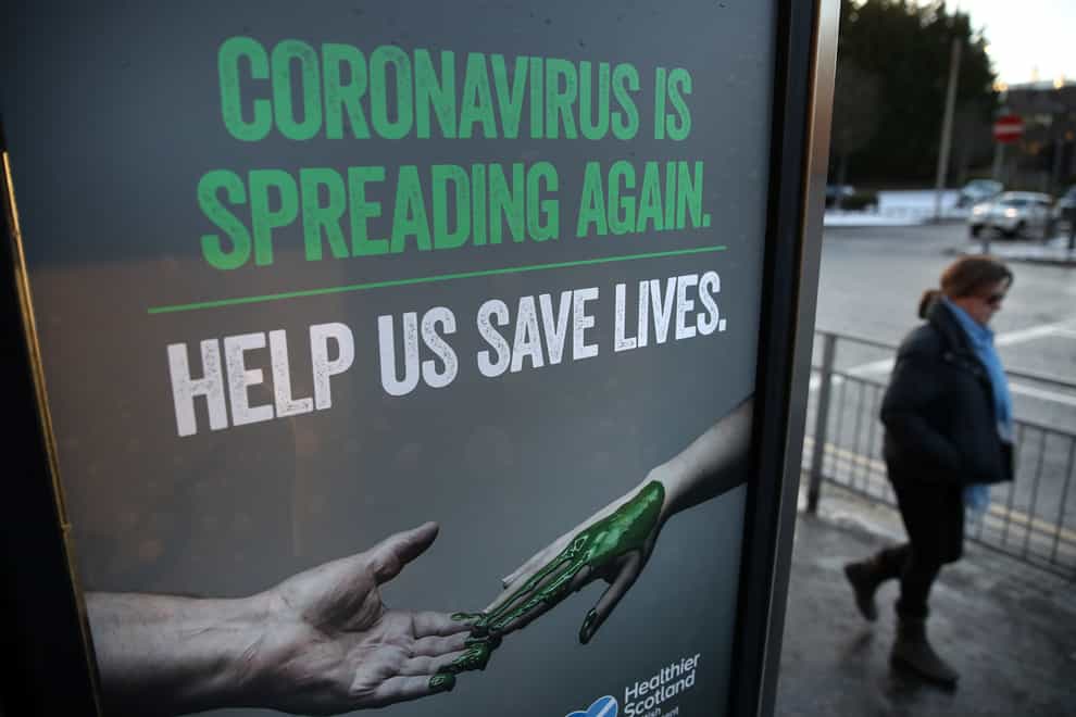 A person walks past a coronavirus-related poster