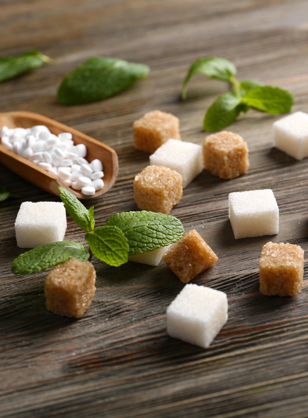 Sugar cubes and stevia on wooden background