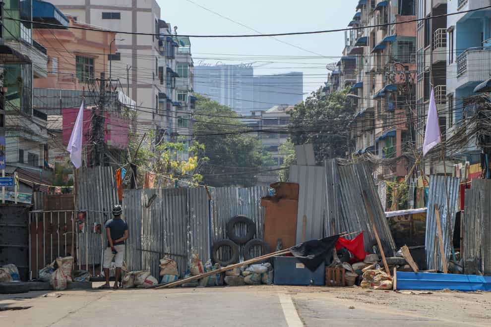 A vigilante stands behind makeshift barricade in Yangon, Myanmar (STR/AP)
