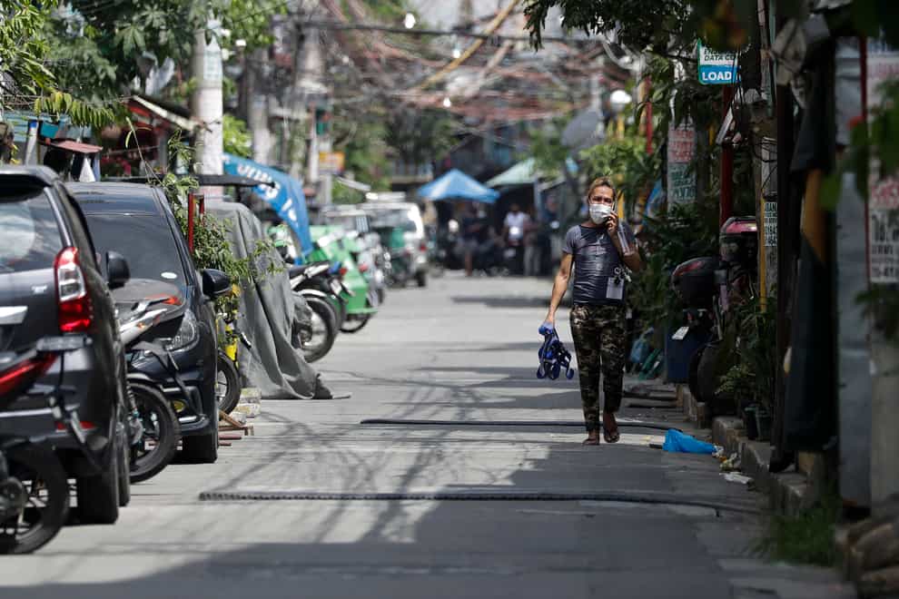 A man walks along an empty street at a village that was placed under lockdown due to the number of Covid-19 cases among residents in Manila, Philippines (Aaron Favila/AP)