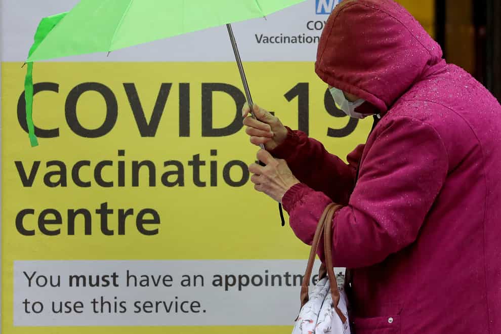 A woman walks past a vaccination centre sign