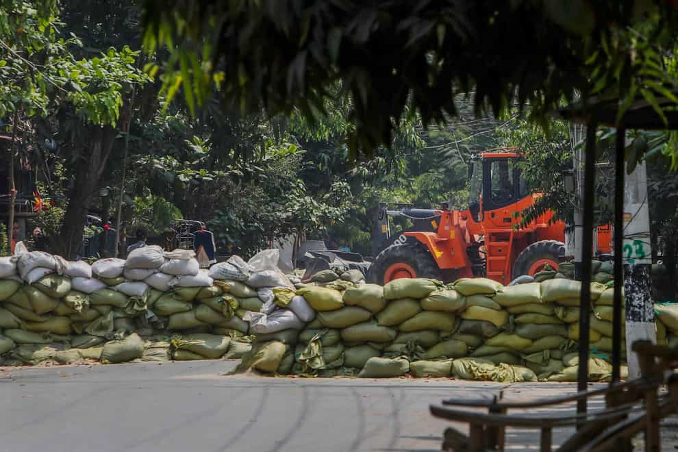 A man watches as soldiers use a bulldozer to remove sandbag barricades put in place by anti-coup protesters to protect them from security forces in Mandalay, Myanmar (STR/PA)