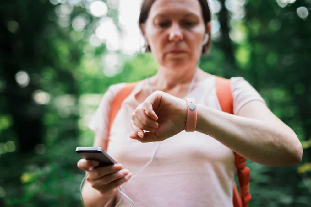 Female hiker checking fitness tracker wristband data