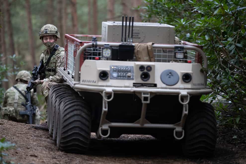 A soldiers next to an unmanned utility delivery vehicle
