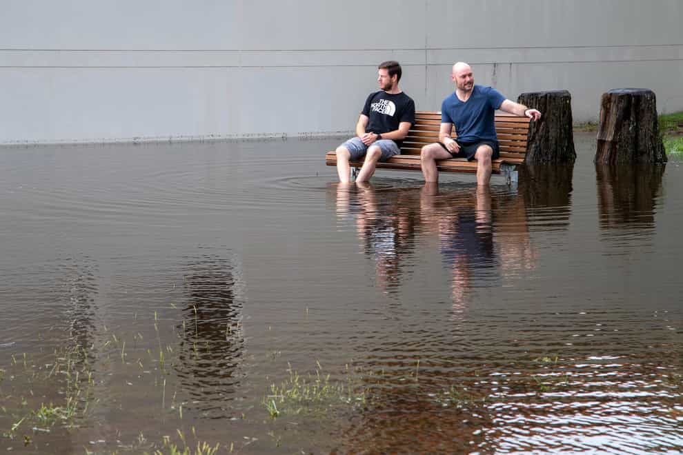 Two men sit on a bench amid flood waters