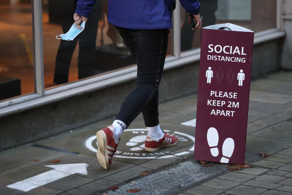 A person walks past a social distancing sign