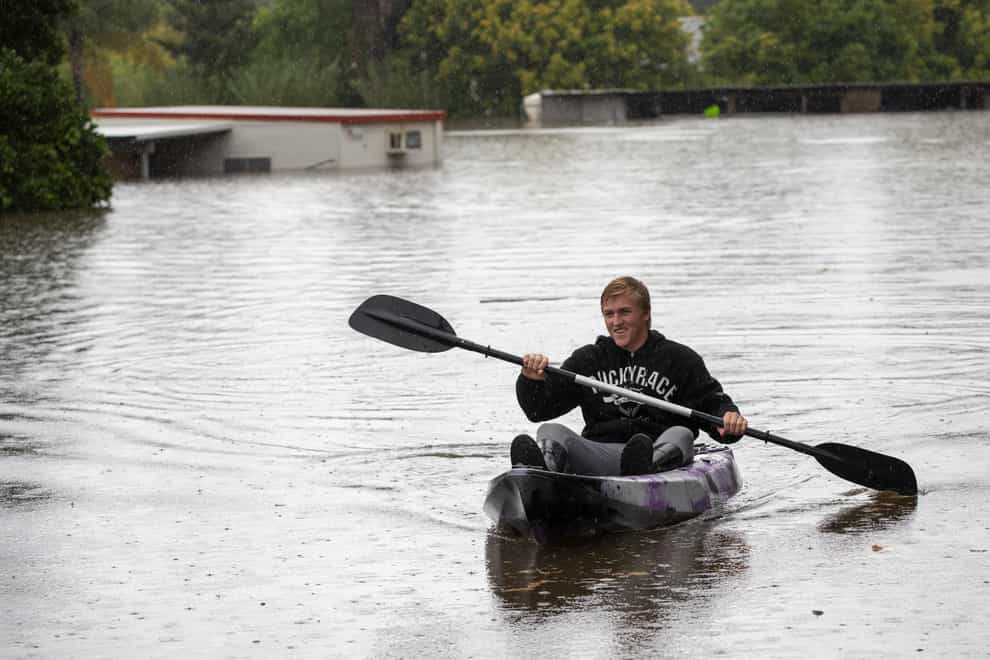 A man paddles through flood waters at Londonderry on the western outskirts of Sydney, Australia