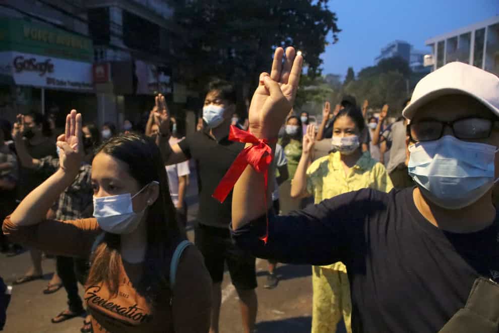 Anti-coup protesters flash three-fingered gesture, a symbol of resistance, during a rally outside their homes in downtown Yangon, Myanmar
