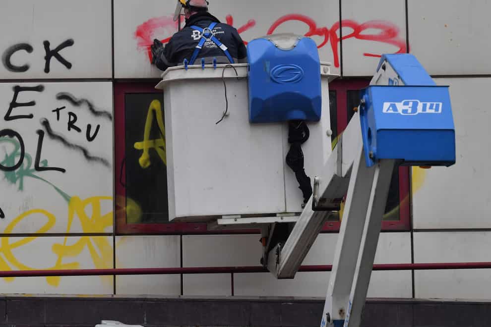A worker from the Bristol BID Team uses a cherry picker to clean graffiti outside of Bridewell police station