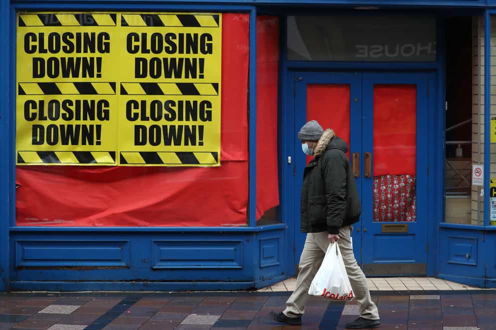 A man walks past a shop with 'Closing down' signs