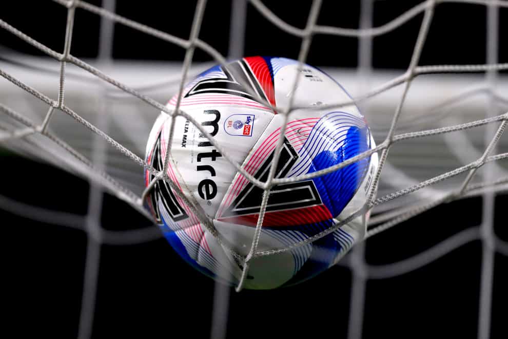A football rests on the roof of a net