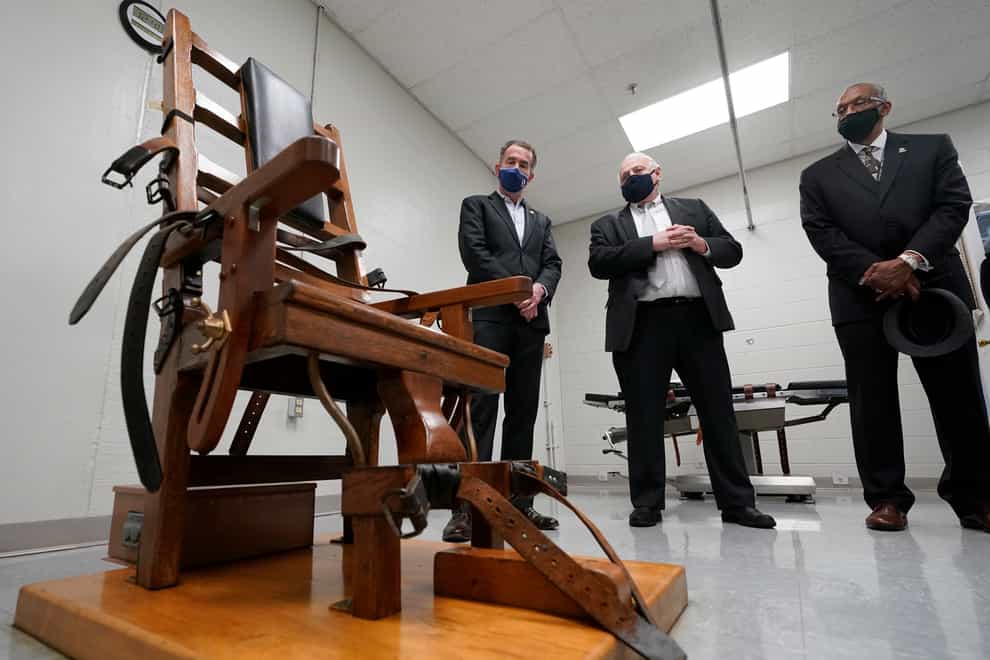 Virginia governor Ralph Northam, left, looks over the electric chair in the death chamber at Greensville Correctional Centre with Operations Director, George Hinkle, center, and Warden Larry Edmonds, right, prior to signing a bill abolishing the death penalty (Steve Heiber/AP)