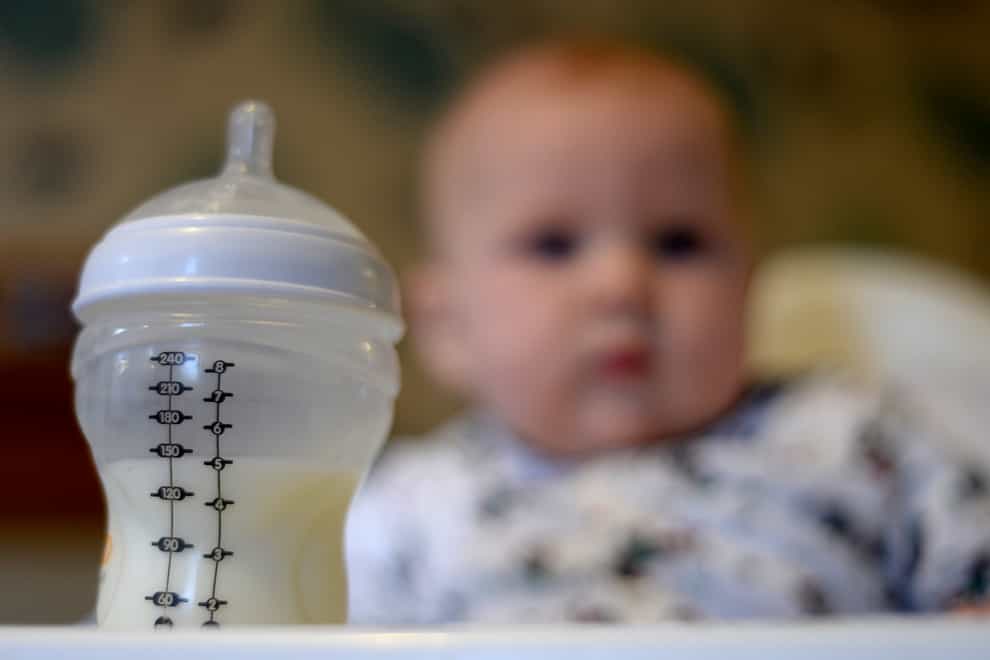 Baby looks at milk bottle