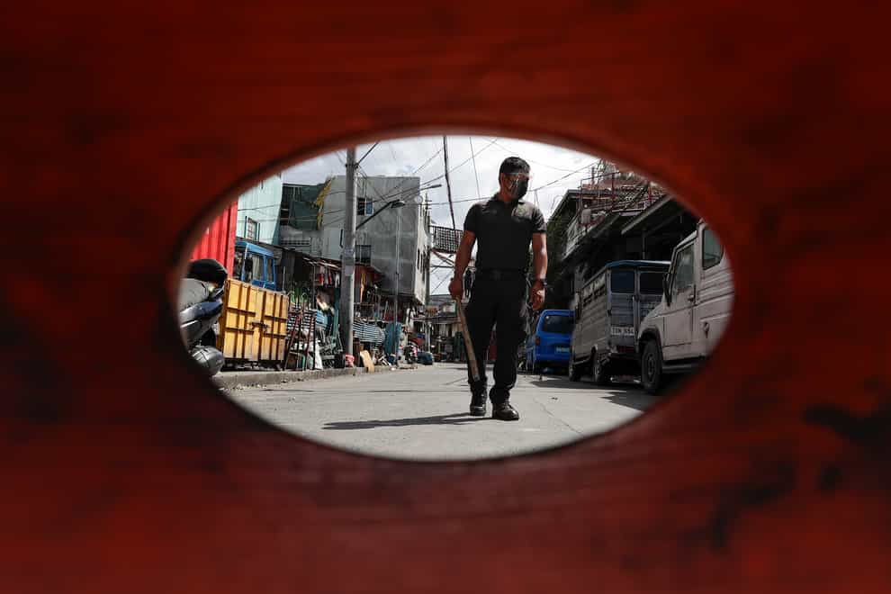 A policeman patrols inside a village that was placed under lockdown as the government implements stricter measures to prevent the spread of coronavirus (Aaron Favila/AP)