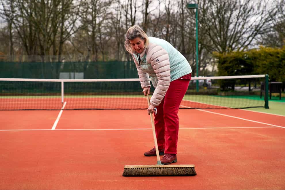 Ruth Williams, welfare officer and ladies captain brushes the courts at Wycombe House Tennis Club in Isleworth, London (John Walton/PA)