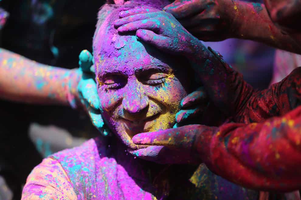 Indians smear coloured powder on each other as they celebrate Holi