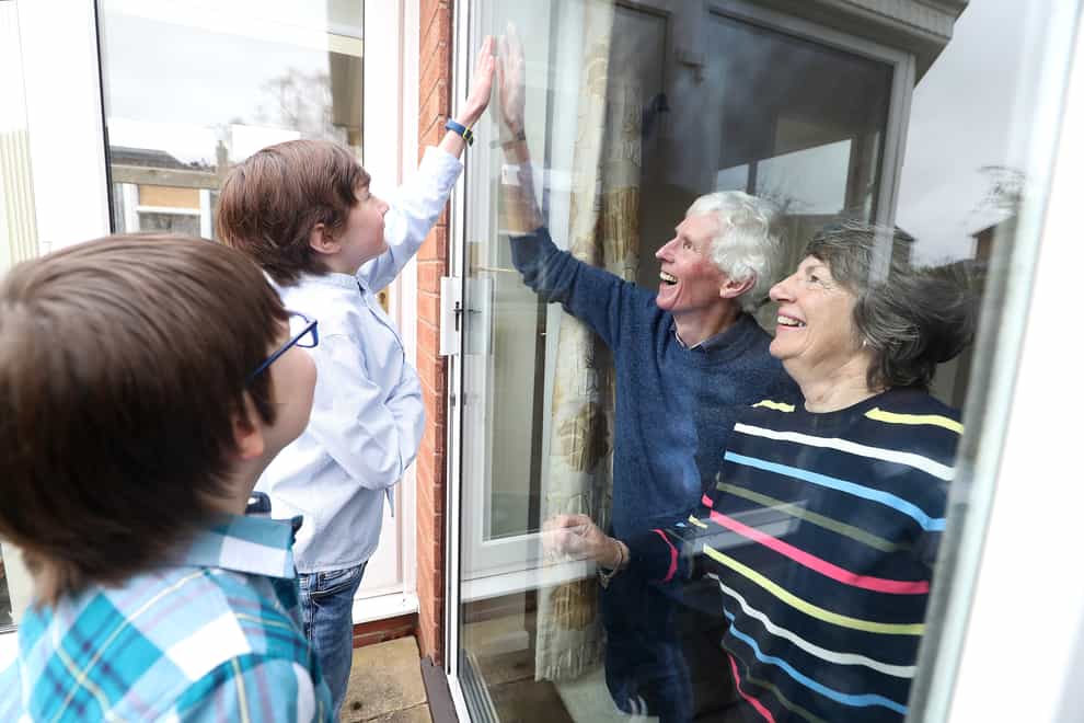 Youngsters talk to their grandparents through a window
