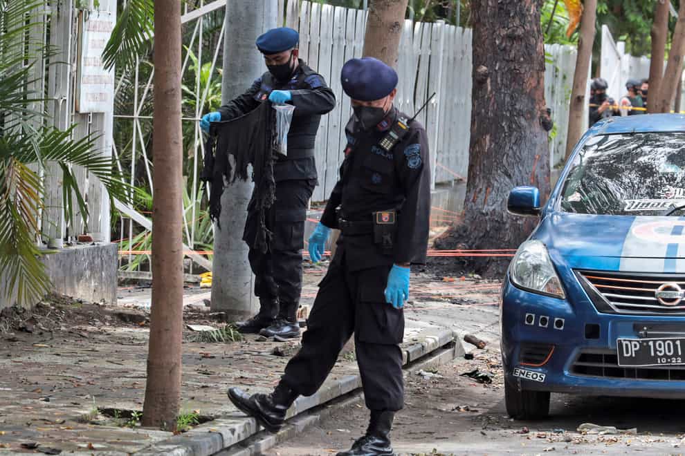 A member of the police bomb squad, left, holds a piece of cloth found at the site of Sunday’s suicide bomb attack at the Sacred Heart of Jesus Cathedral in Makassar, South Sulawesi, Indonesia (Yusuf Wahil/AP)