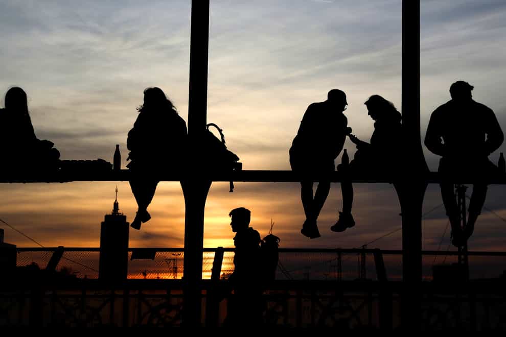Young people enjoy the sunset at the bridge ‘Hackerbruecke’ in Munich, Germany (Matthias Schrader/AP)