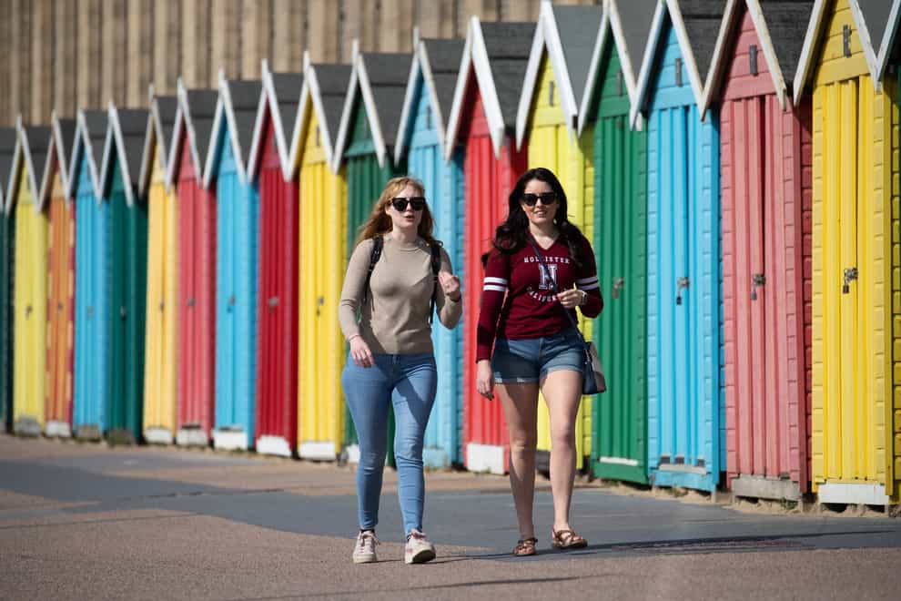 People make their way past beach huts on the sea front on Boscombe beach in Dorset