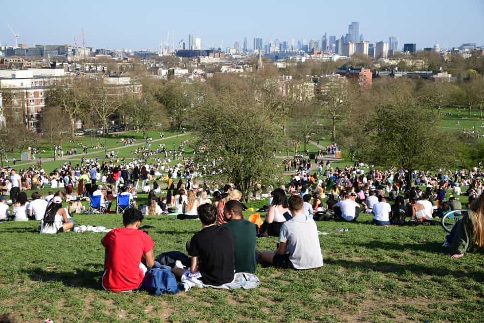 Groups of people sit in a park and enjoy the sunshine