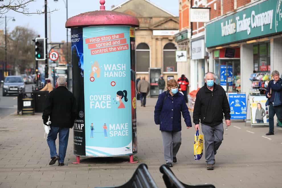 People wearing face masks walk past a coronavirus advice sign in Skegness, Lincolnshire (Mike Egerton/PA)