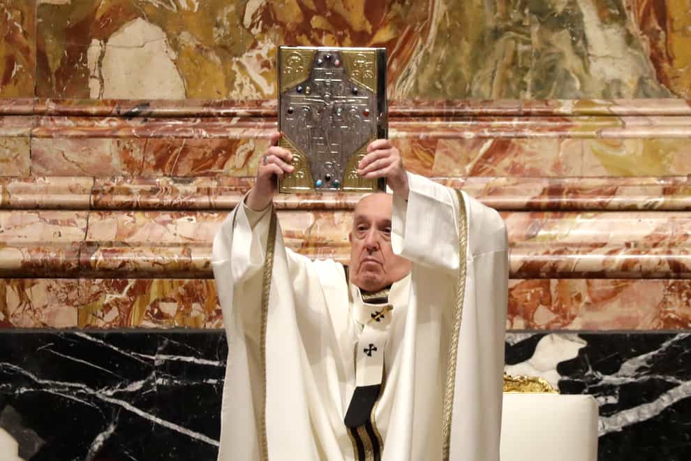 Pope Francis holds up the book of Gospels during a Chrism Mass inside St Peter’s Basilica at the Vatican