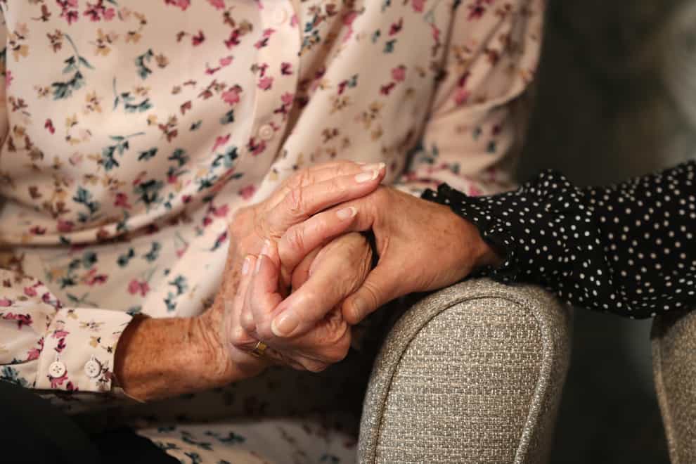 A care home resident holds hands with her daughter as part of a care group's enhanced visiting scheme. (Andrew Matthews/PA)