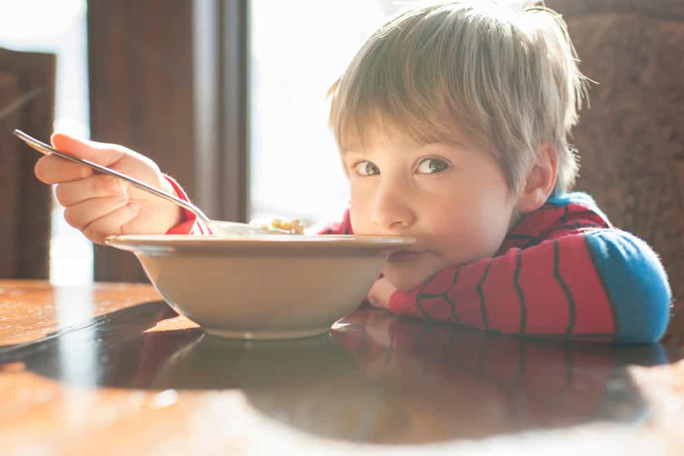 Portrait of boy eating food while leaning on table at home