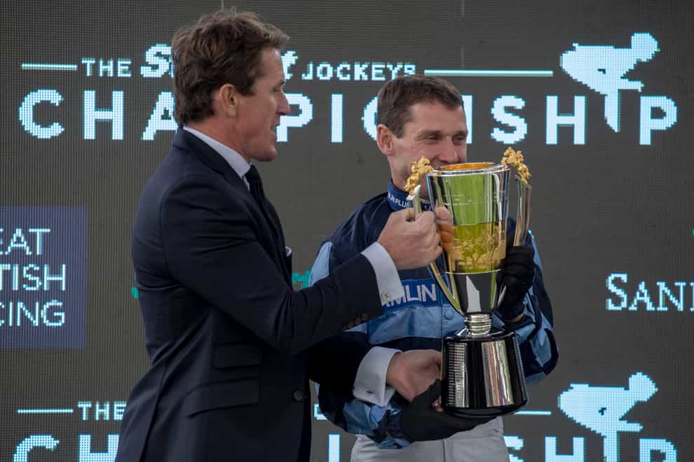 Richard Johnson is presented with the champion jump jockey trophy by Sir Anthony McCoy at Sandown