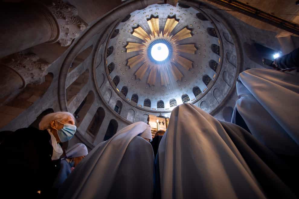 A woman wearing a face mask attends Easter Sunday mass led by Latin Patriarch of Jerusalem Pierbattista Pizzaballa at the Church of the Holy Sepulchre, where Jesus Christ is believed to have been buried, in the Old City of Jerusalem (Oded Balilty/AP)