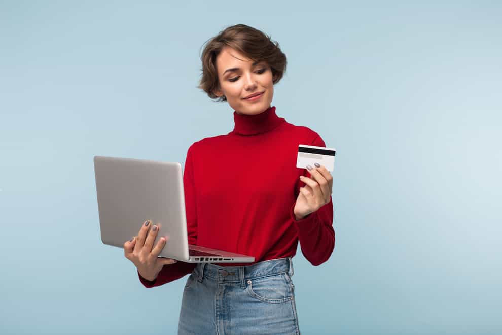 Woman with laptop and credit card, thinking carefully