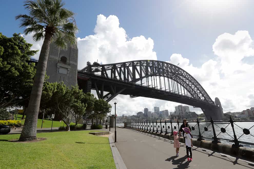 A woman and two children walk under the Harbour Bridge in a popular area in Sydney, Australia