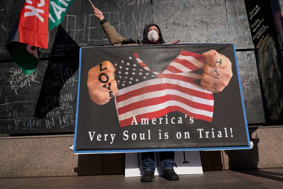 A protester holds a sign across the street from the Hennepin County Government Centre (Jim Mone/AP)
