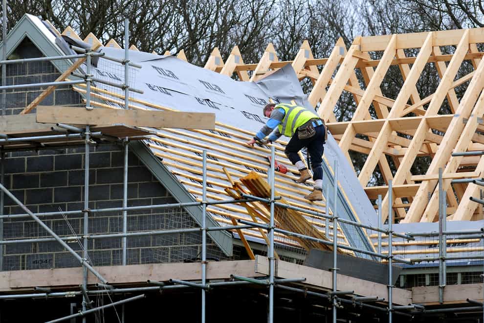 A roofer works on a new house building project