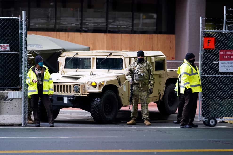 A National Guard soldier, centre, stands guard with deputies at the restricted vehicle entrance of the Hennepin County Government Centre (Jim Mone/AP)