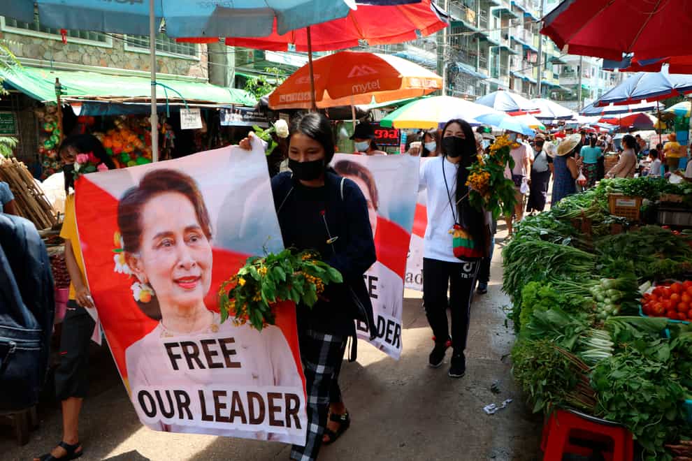 Protesters walk through Myanmar, Yangon, with a banner of Aung San Suu Kyi