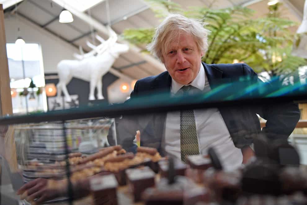 Prime Minister Boris Johnson looks at a display of cakes and desserts as he talks with business owners during a visit to Lemon Street Market in Truro, Cornwall to see how they are preparing to reopen ahead of Step 2 of the road map (Justin Tallis/PA)
