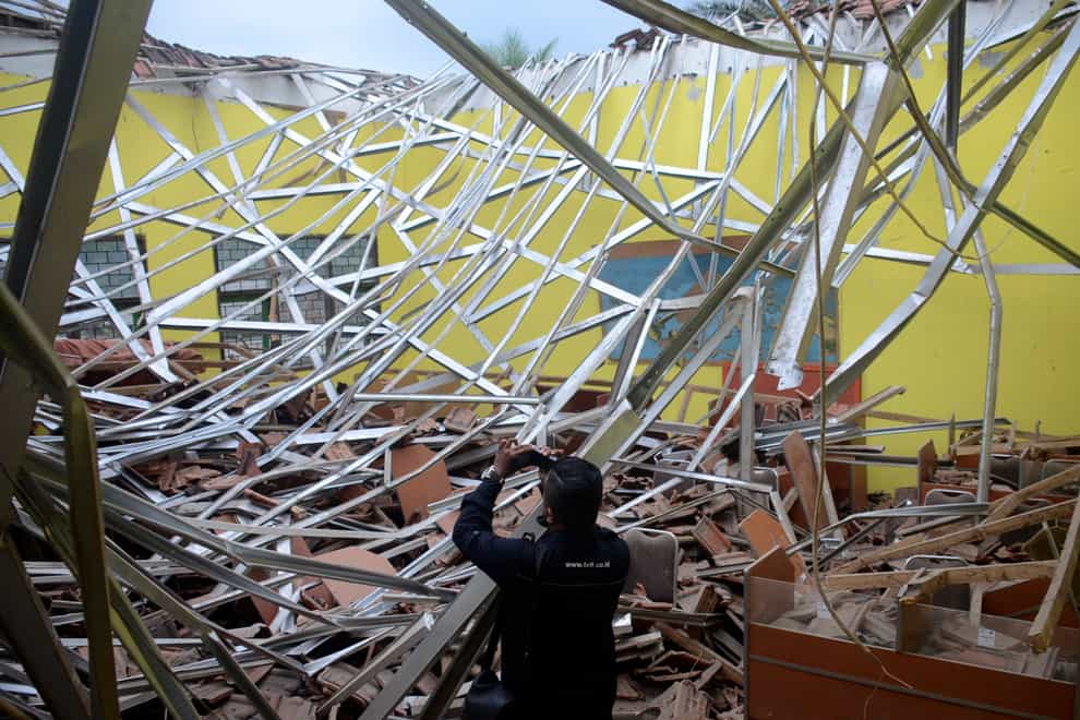 A journalist films earthquake damage to a school in Malang, East Java