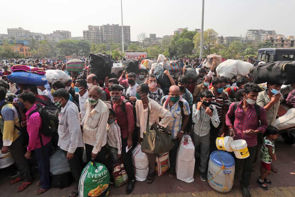 People wearing masks stand in queues to board trains at Lokmanya Tilak Terminus in Mumbai, India