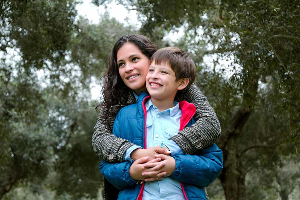Woman with her arms around her son, out in nature
