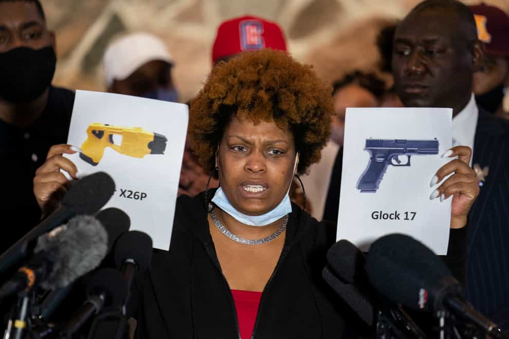 Naisha Wright, aunt of the deceased Daunte Wright, holds up images depicting X26P Taser and a Glock 17 handgun (John Minchillo/AP)